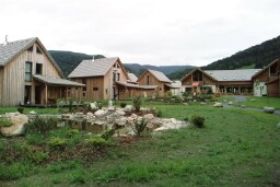 die Ferienparkanlage, rechts ein kleiner See, im Hintergrund der Spielplatz und das Empfangsgebaeude. Dort finden Sie das Hallenbad, die Sauna, ein Restaurant und den Shop fuer die Fruehstuecksbroetchen.
