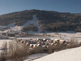 Der Ferienpark im Winter mit Blick auf die Skiabfahrt des Kreischbergs und links die Snowboardarena